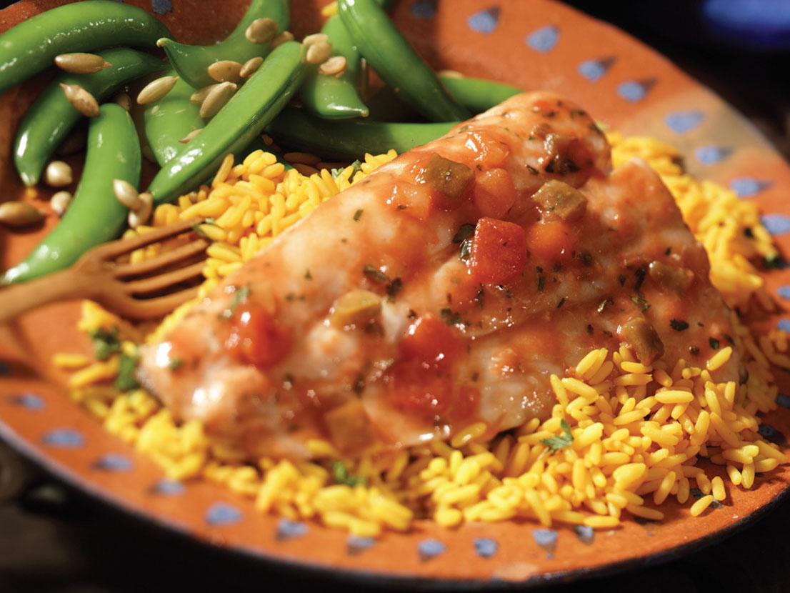 An image of prepared Cod Veracruz made with cod, Campbell's® Condensed Tomato Soup, Campbell's® Condensed Chicken Broth, Pace® Picante Sauce, olives, cilantro and rice.