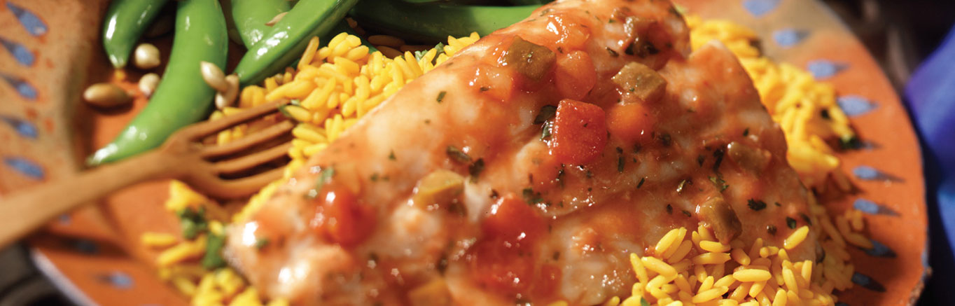 An image of prepared Cod Veracruz made with cod, Campbell's® Condensed Tomato Soup, Campbell's® Condensed Chicken Broth, Pace® Picante Sauce, olives, cilantro and rice.