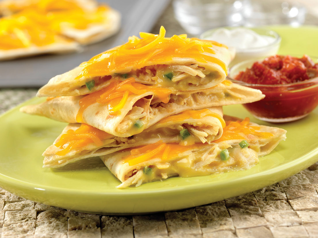 An image of prepared Creamy Chicken Quesadillas made with Campbell's® Condensed Cream of Chicken Soup, Cheddar cheese, jalapeño, Swanson® Premium White Chunk Chicken, flour tortillas, Pace® Chunky Salsa and sour cream.