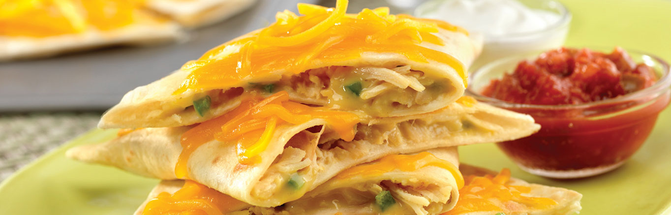 An image of prepared Creamy Chicken Quesadillas made with Campbell's® Condensed Cream of Chicken Soup, Cheddar cheese, jalapeño, Swanson® Premium White Chunk Chicken, flour tortillas, Pace® Chunky Salsa and sour cream.