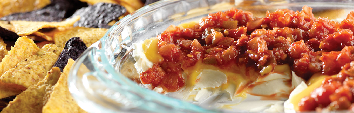 An image of prepared Easy Layered Dip made with cream cheese, Campbell's® Condensed Cheddar Cheese Soup, Pace® Chunky Salsa and tortilla chips.