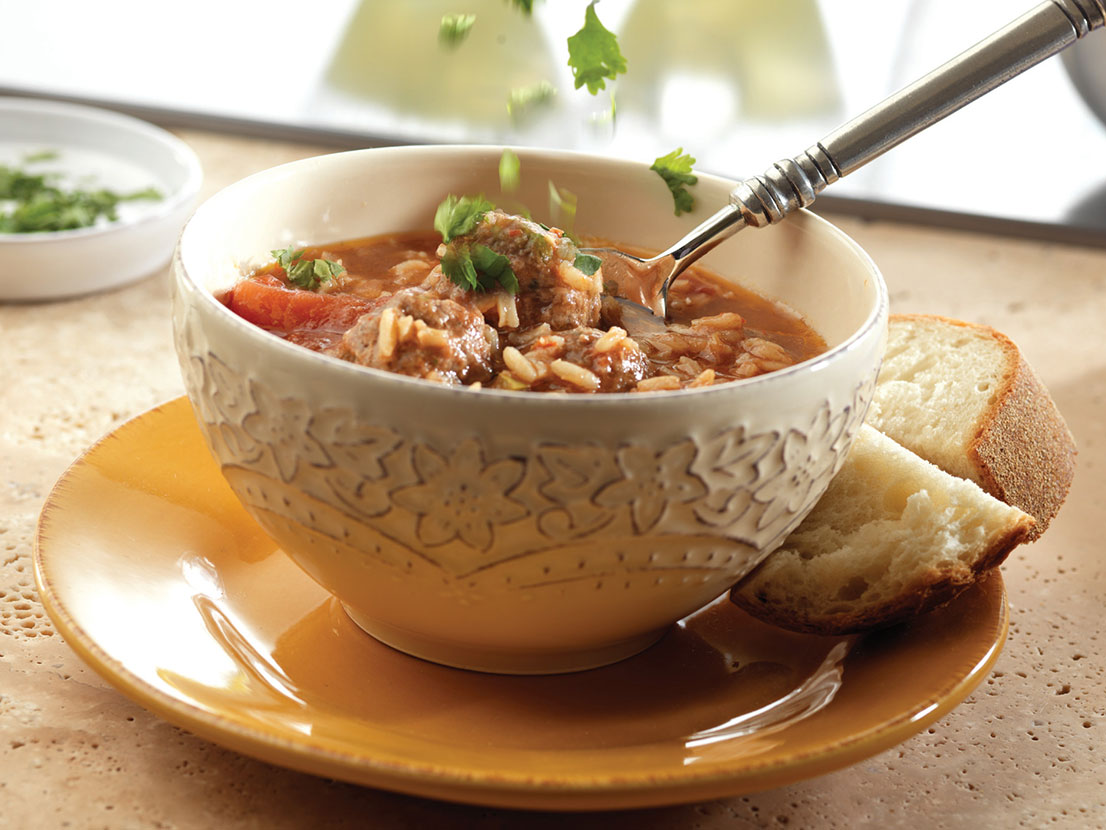 An image of prepared Albondigas Soup made with ground beef, cornmeal, cilantro, Swanson® Beef Broth, Pace® Chunky Salsa, tomatoes, garlic and long grain white rice.