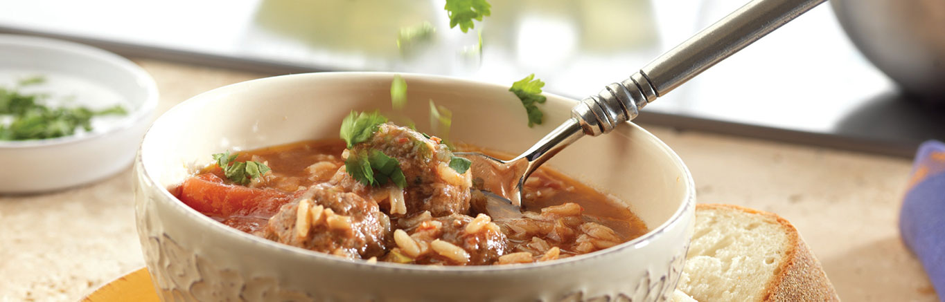 An image of prepared Albondigas Soup made with ground beef, cornmeal, cilantro, Swanson® Beef Broth, Pace® Chunky Salsa, tomatoes, garlic and long grain white rice.