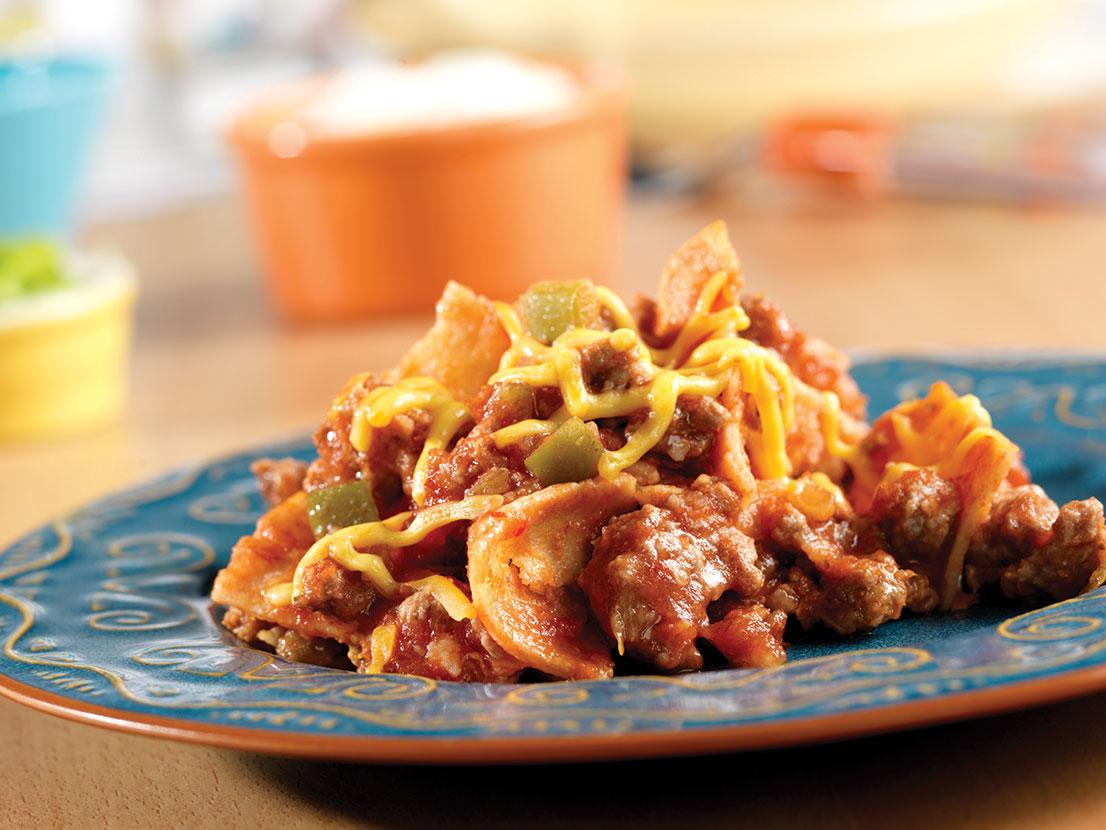 An image of prepared Beefy Enchilada Skillet made with ground beef, Pace® Picante Sauce, tortillas, Cheddar cheese, sour cream and green onion.
