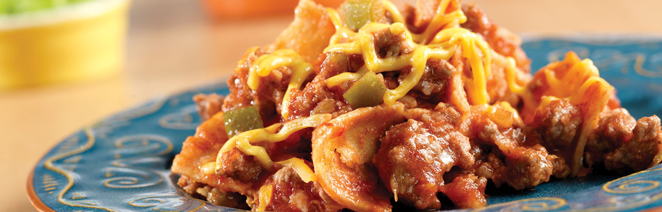 An image of prepared Beefy Enchilada Skillet made with ground beef, Pace® Picante Sauce, tortillas, Cheddar cheese, sour cream and green onion.