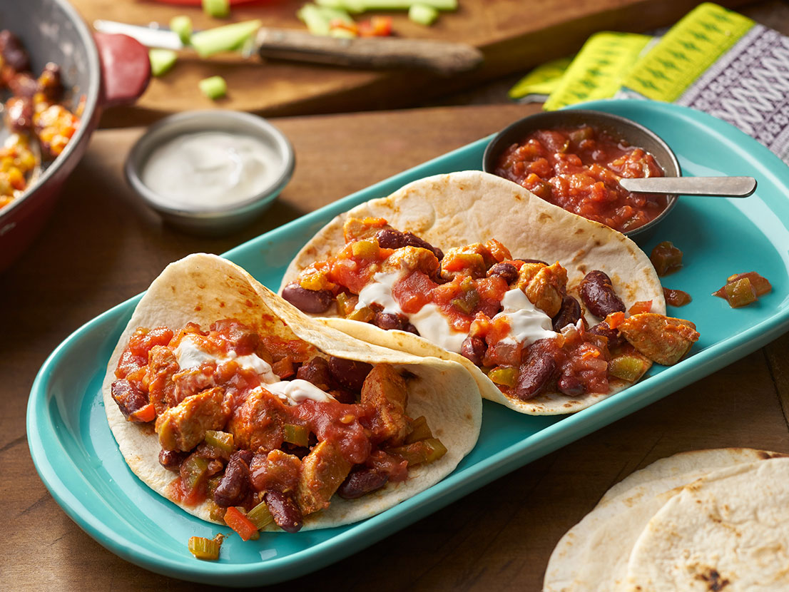 An image of prepared Cajun Chicken Tacos made with chicken, Cajun seasoning, Pace® Chunky Salsa, bell pepper, kidney beans, sour cream and tortillas.
