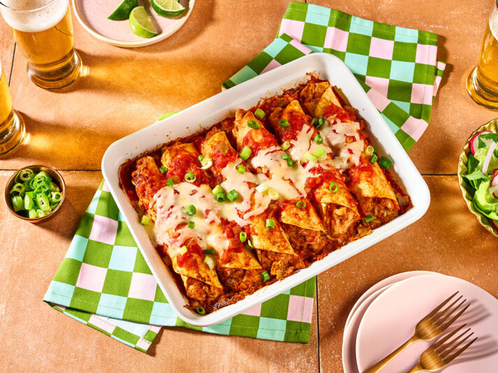 An image of prepared Chicken Enchiladas made with Pace® Mild Enchiladas Sauce, chicken, Monterey Jack cheese, sour cream, tortillas and green onion.