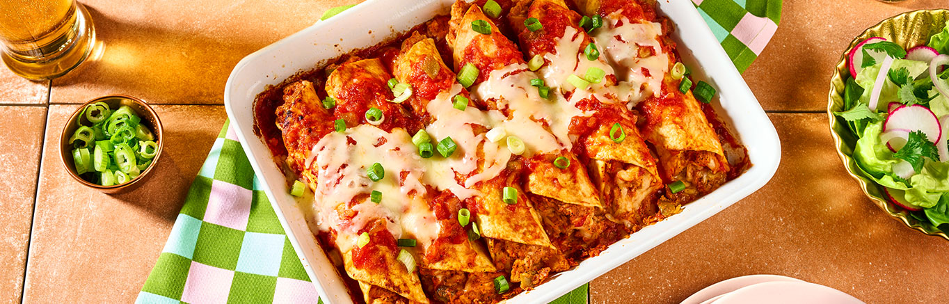 An image of prepared Chicken Enchiladas made with Pace® Mild Enchiladas Sauce, chicken, Monterey Jack cheese, sour cream, tortillas and green onion.