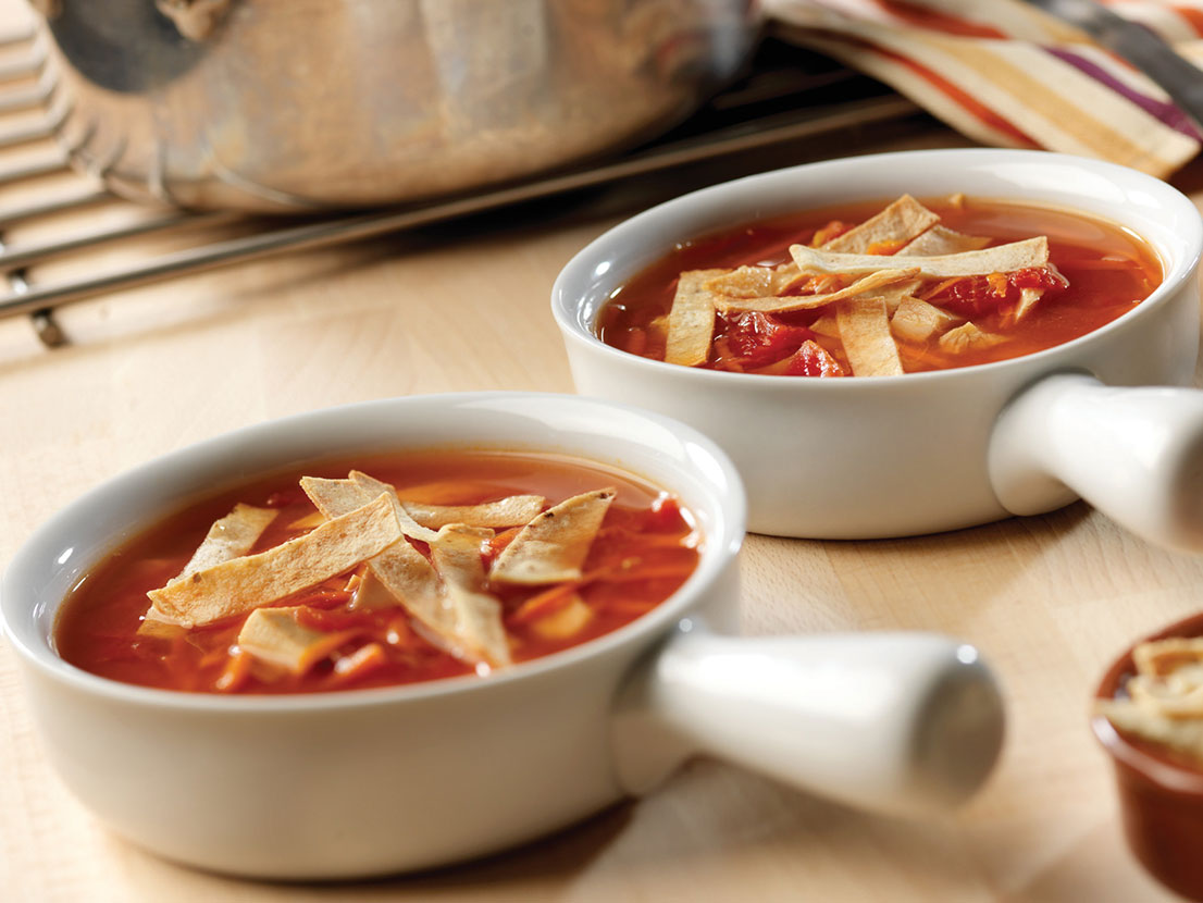 An image of prepared Chicken Tortilla Soup made with corn tortillas, Swanson® Chicken Broth, Pace® Picante Sauce, tomatoes, carrots and chicken.