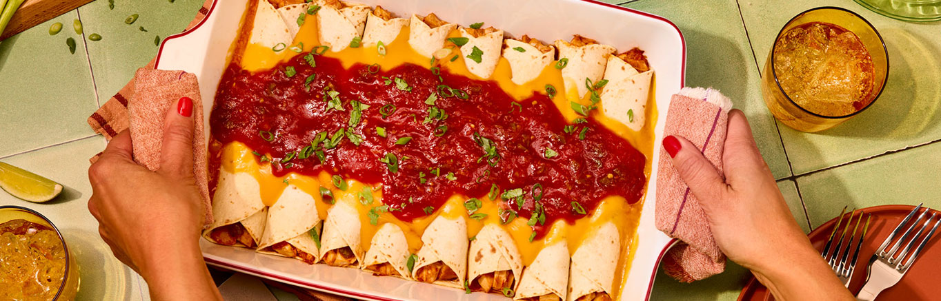 An image of prepared Chicken & Cheese Enchiladas made with Pace® Picante Sauce, Pace® Mild Nacho Cheese Sauce, chicken, cumin and flour tortillas.