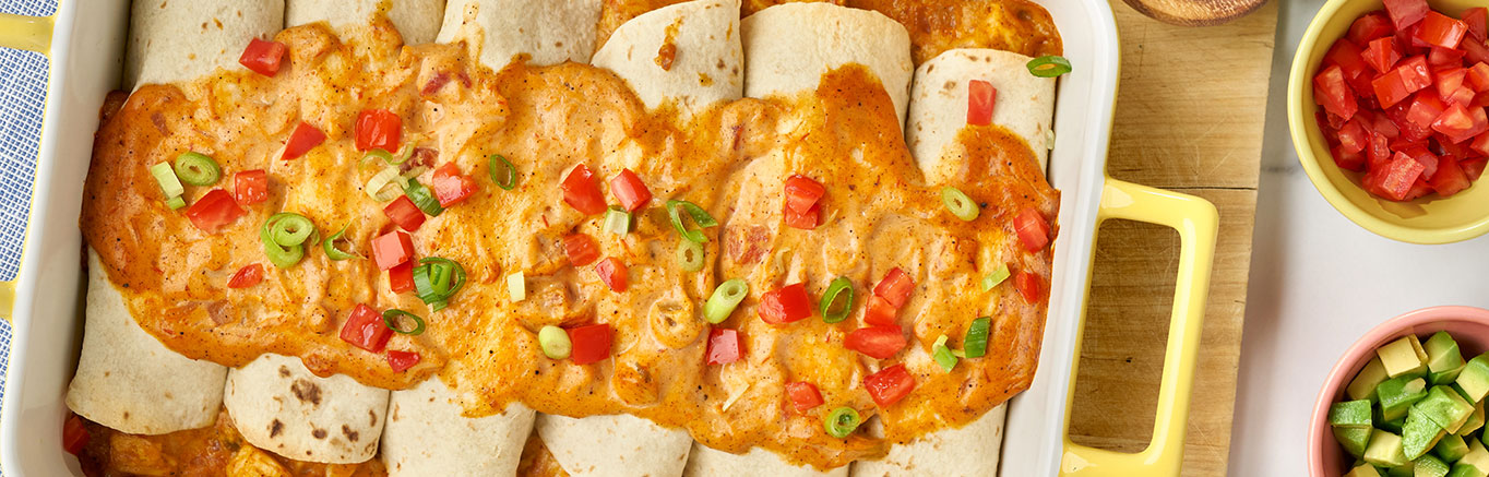 An image of prepared Easy Chicken & Cheese Enchiladas made with Pace® Picante Sauce, Campbell's® Condensed Cream of Chicken Soup, sour cream, chili powder, chicken, Monterey Jack cheese, flour tortillas, tomatoes and green onion.