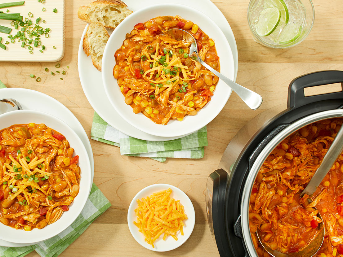An image of prepared Instant Pot® White Chicken Chili made with red bell pepper, corn, chicken, white cannellini beans, Pace® Chunky Salsa, Campbell's® Condensed Cream of Chicken Soup, Cheddar cheese and green onion.