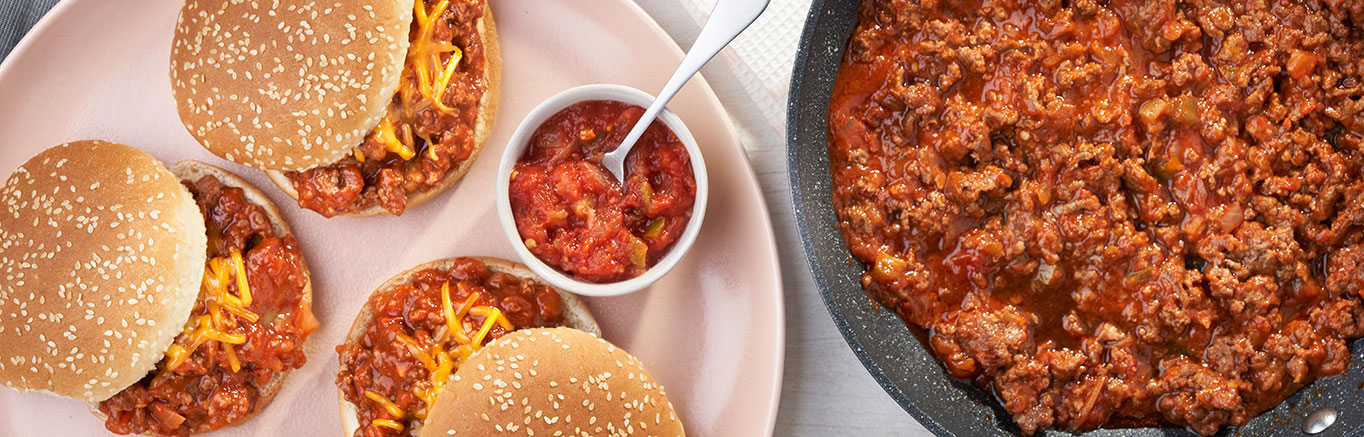 An image of prepared Zesty Taco Sloppy Joes showing ground beef, Campbell's® Condensed Tomato Soup, Pace® Chunky Salsa and Cheddar cheese on Pepperidge Farm® Sesame Topped Hamburger Buns.