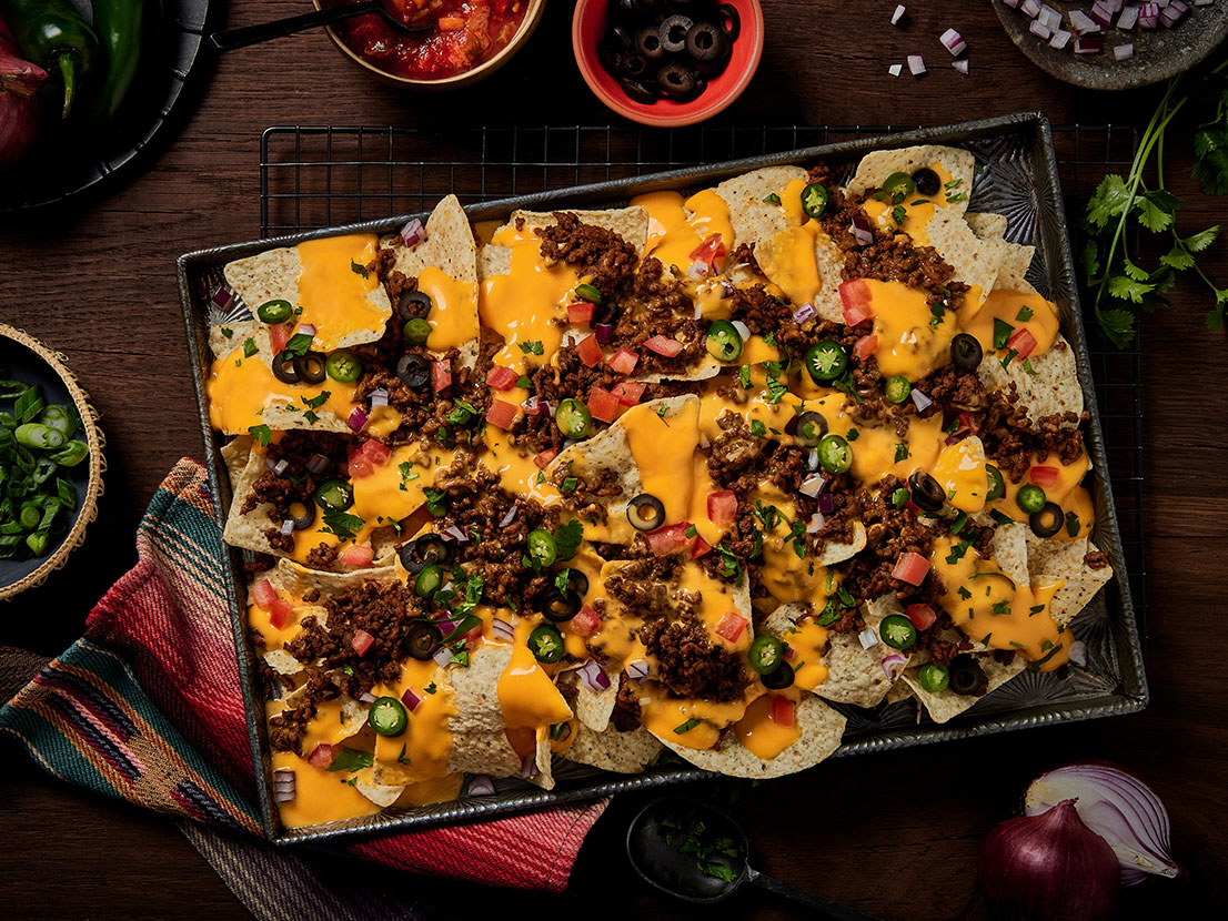 An image of prepared Loaded Nachos made with ground beef, taco seasoning, Pace® Mild Nacho Cheese Sauce and tortilla chips.