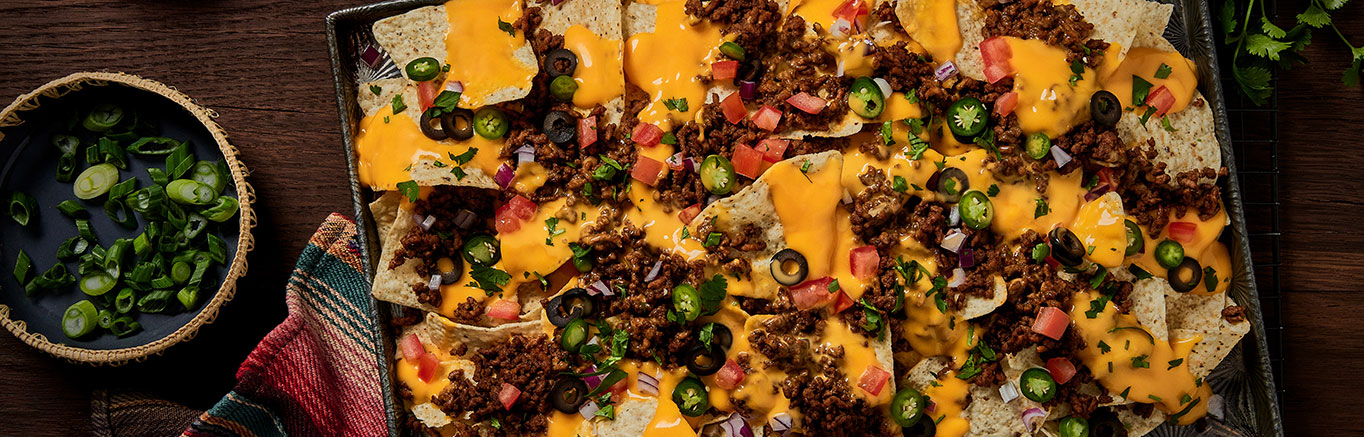 An image of prepared Loaded Nachos made with ground beef, taco seasoning, Pace® Mild Nacho Cheese Sauce and tortilla chips.