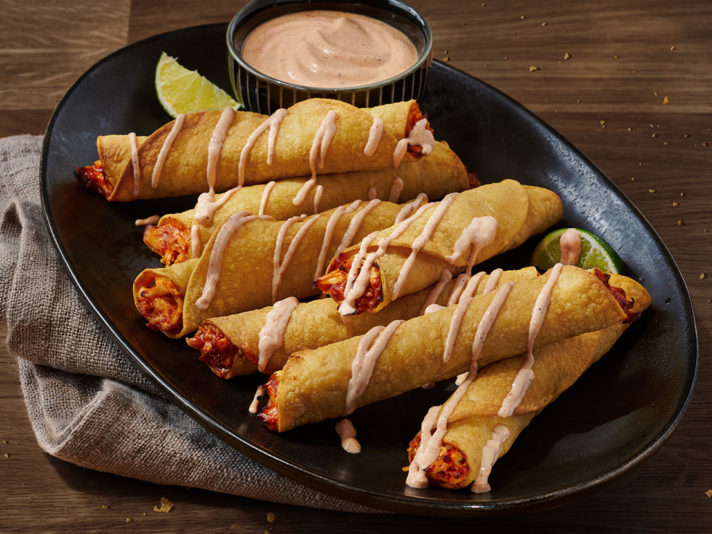 An image of prepared Air-Fryer Chicken Taquitos made with cooked chicken, Pace® Mild Enchilada Sauce, Cheddar cheese, corn tortillas and sour cream.