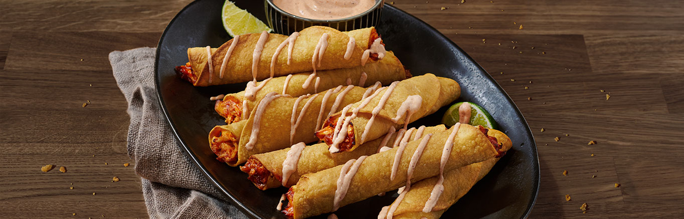 An image of prepared Air-Fryer Chicken Taquitos made with cooked chicken, Pace® Mild Enchilada Sauce, Cheddar cheese, corn tortillas and sour cream.