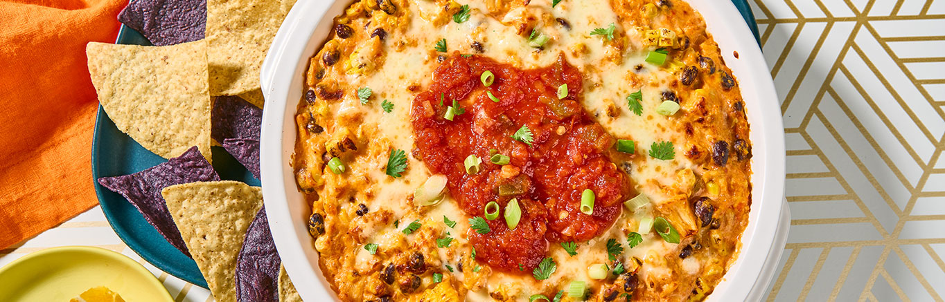 An image of prepared Creamy Salsa Chicken Dip made with Swanson® Premium White Chicken Breast, black beans, corn, Pace® Chunky Salsa, cream cheese, Monterey Jack and green onion.