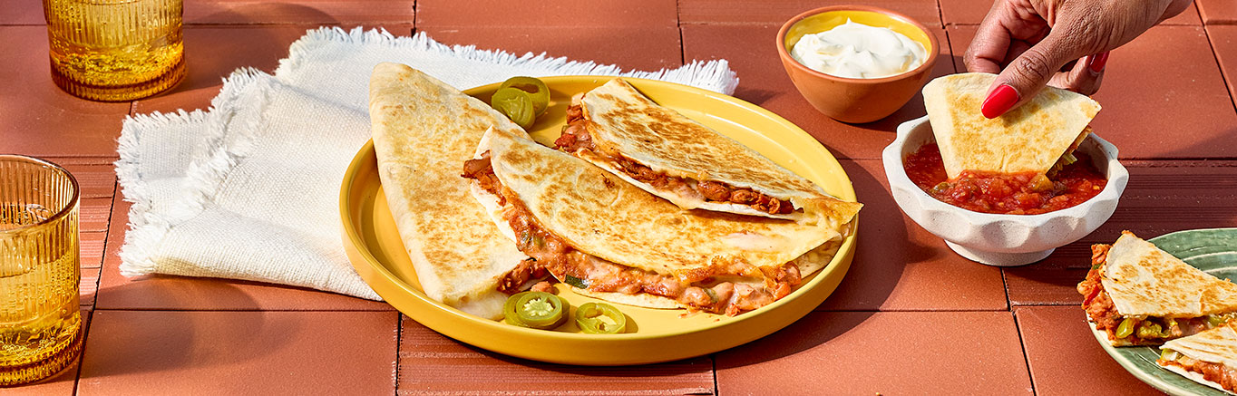 An image of prepared Hearty Pinto Bean Quesadillas made with green onion, pinto beans, Pace® Picante Sauce, Pace® Signature Classic Taco Sauce, Monterey Jack cheese and flour tortillas.