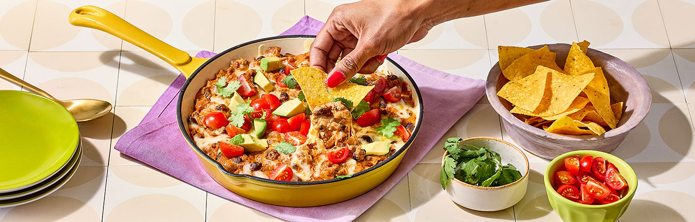 An image of prepared Creamy Taco Dip made with ground beef, red onion, garlic, black beans, Pace® Picante Sauce, Pace® Signature Sauces Hot Honey Chipotle Sauce, cream cheese and pepper Jack cheese.