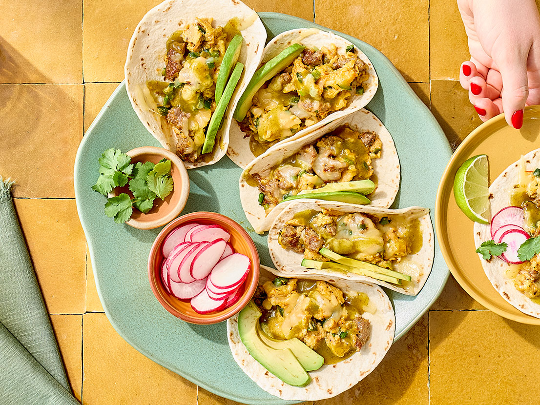 An image of prepared Breakfast Tacos with Eggs & Sausage made with eggs, pork breakfast sausage, poblano chile, Pace® Chunky Salsa or Picante Sauce, flour tortillas, Pepper Jack cheese and Pace® Cilantro Jalapeño Lime Signature Sauce.