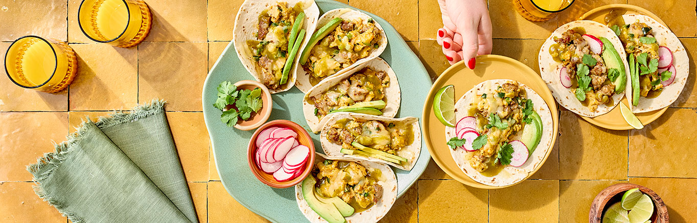 An image of prepared Breakfast Tacos with Eggs & Sausage made with eggs, pork breakfast sausage, poblano chile, Pace® Chunky Salsa or Picante Sauce, flour tortillas, Pepper Jack cheese and Pace® Cilantro Jalapeño Lime Signature Sauce.