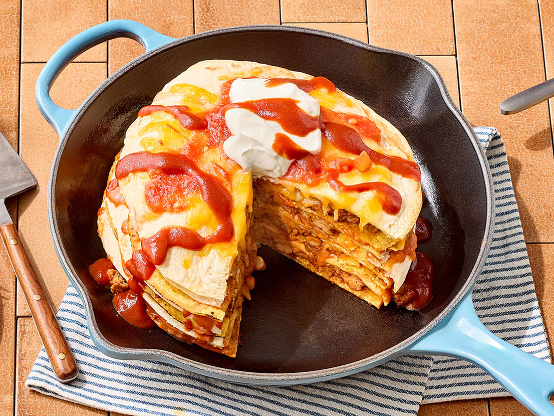 An image of prepared Cheesy Taco Stack made with ground turkey, taco seasoning, Pace® Picante Sauce, flour tortillas, Pace® Salsa con Queso, Pace® Signature Classic Taco Sauce, tostada shells, Colby Jack cheese and sour cream.