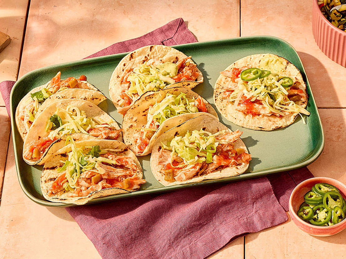 An image of prepared Cilantro Jalapeño Lime Chicken Tacos made with avocado, Pace® Signature Sauces Cilantro Jalapeño Lime Sauce, cilantro, green cabbage, chicken, Pace® Picante Sauce and corn tortillas.