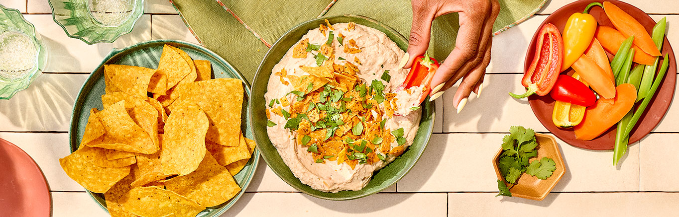 An image of prepared Creamy Mexican Ranch Dip made with cream cheese, sour cream, ranch dressing, Pace® Chunky Salsa, Pace® Signature Sauces Cilantro Jalapeño Lime Sauce and tortilla chips.