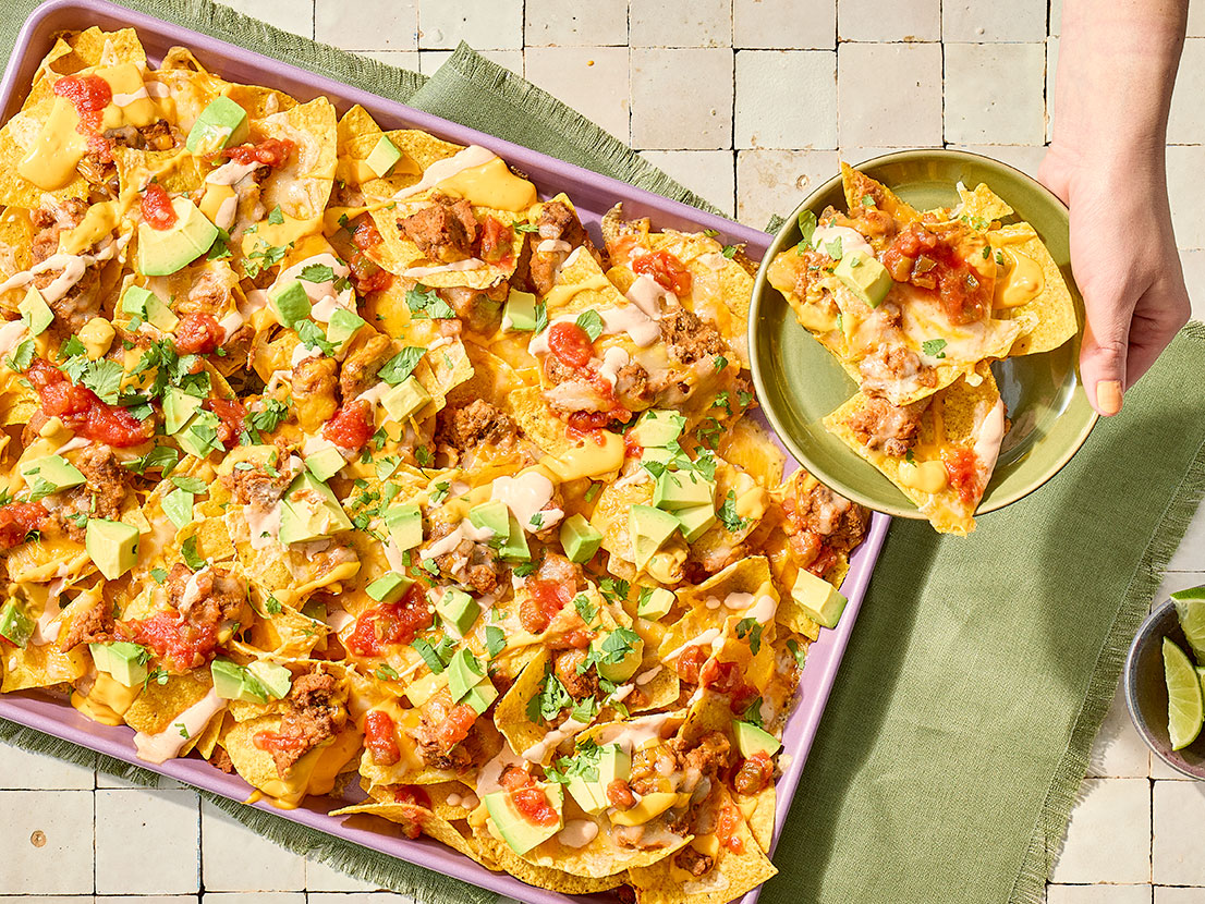 An image of prepared Easy Game Day Nachos made with ground beef, refried beans, Pace® Picante Sauce, Pace® Hot Honey Chipotle Signature Sauce, tortilla chips, Colby Jack cheese, sour cream, Pace® Salsa Con Queso and avocado.