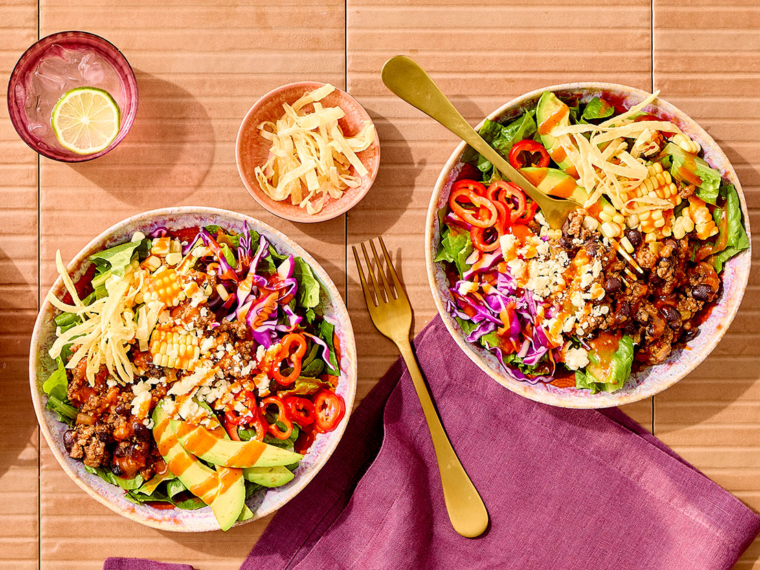 An image of prepared Mexican Salad made with ground beef, black beans, Pace® Chunky Salsa or Picante Sauce, Pace® Signature Sauces Hot Honey Chipotle Sauce, romaine, corn, tortilla strips, avocado and cotija cheese.