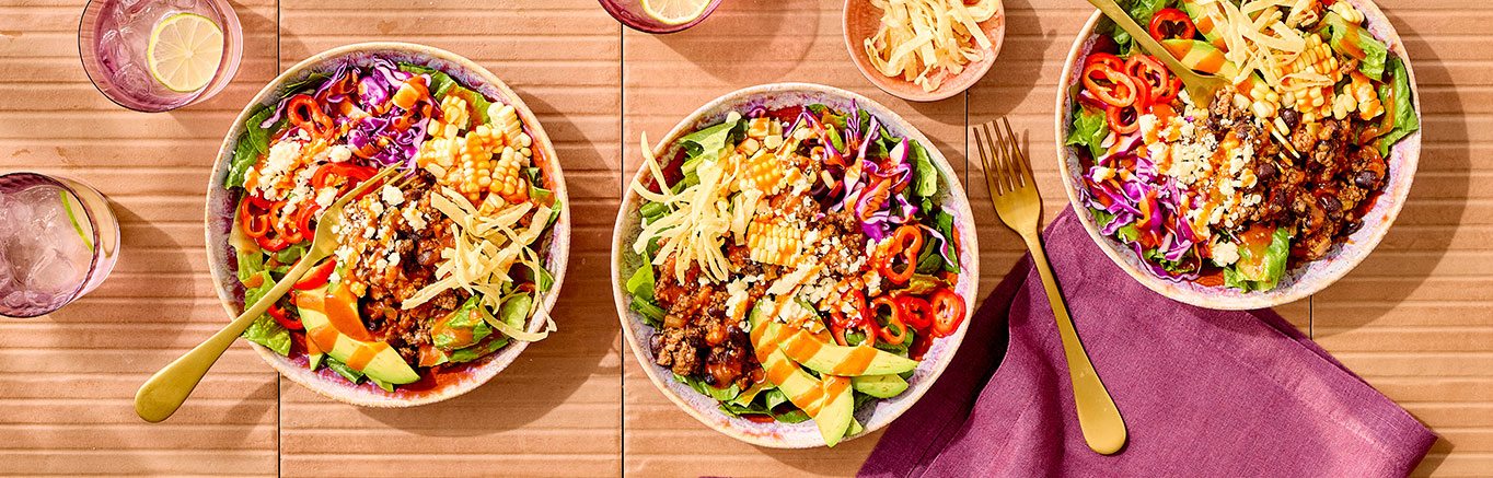 An image of prepared Mexican Salad made with ground beef, black beans, Pace® Chunky Salsa or Picante Sauce, Pace® Signature Sauces Hot Honey Chipotle Sauce, romaine, corn, tortilla strips, avocado and cotija cheese.
