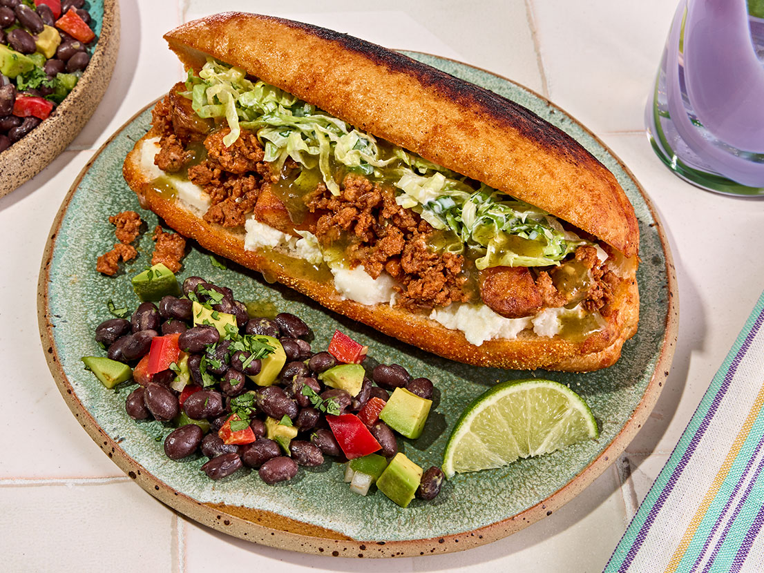 An image of prepared Mexican Chorizo & Potato Sandwich (Pambazo) made with Yukon Gold potatoes, Mexican chorizo sausage, Pace® Signature Sauces Classic Taco Sauce, iceberg lettuce, cilantro and hoagie rolls.
