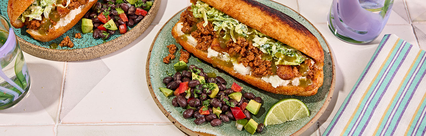 An image of prepared Mexican Chorizo & Potato Sandwich (Pambazo) made with Yukon Gold potatoes, Mexican chorizo sausage, Pace® Signature Sauces Classic Taco Sauce, iceberg lettuce, cilantro and hoagie rolls.