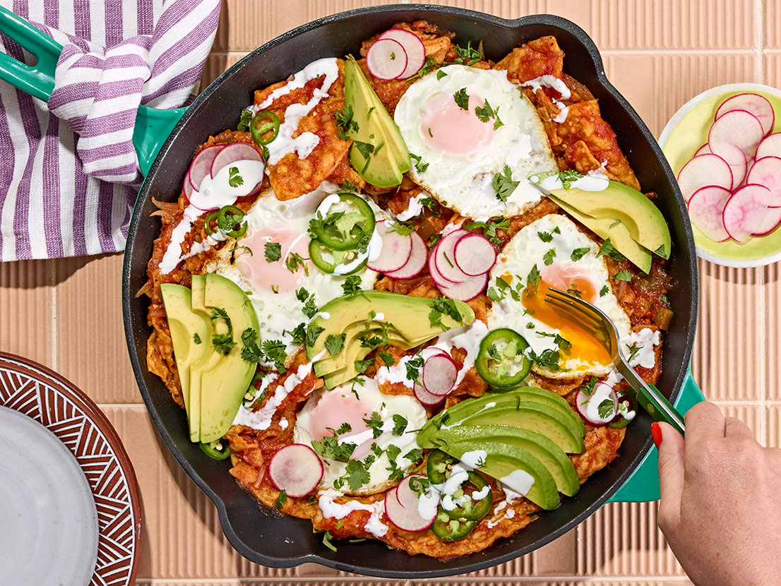 An image of prepared Shortcut Chilaquiles made with eggs, onion, garlic, Pace® Picante Sauce, Swanson® Unsalted Chicken Broth, tortilla chips, avocado, crema Mexicana and cilantro.