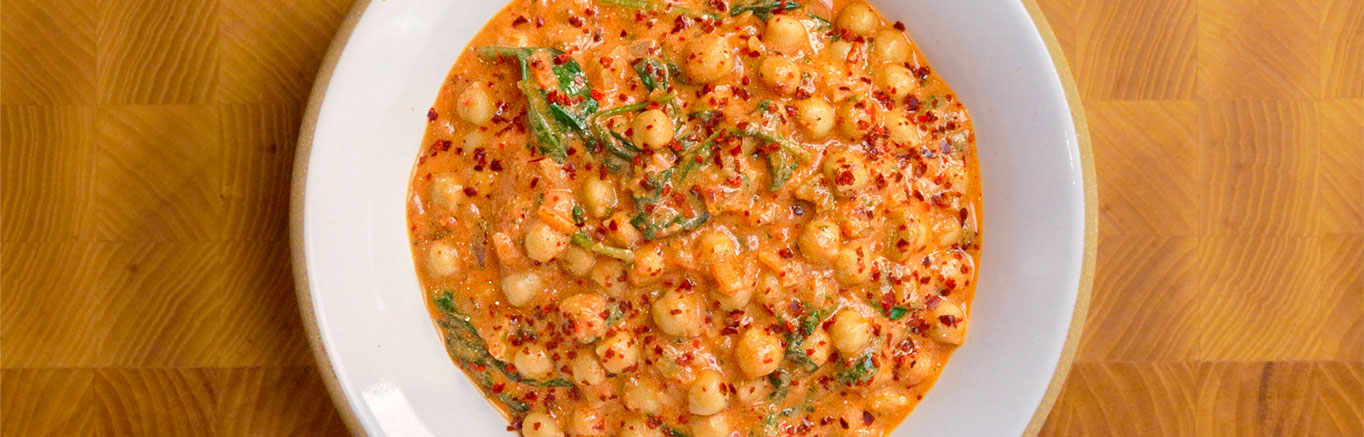 An image of prepared Creamy Picante Chickpea Stew made with onion, chickpeas, Pace® Picante Sauce, Swanson® Chicken Stock, sour cream and baby spinach.