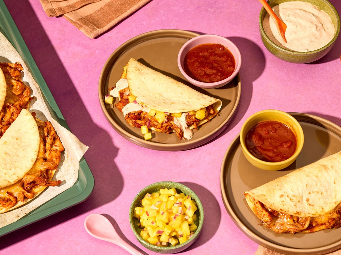 An image of prepared Sheet Pan Chipotle Chicken Tacos made with chicken thighs, Pace® Chipotle Picante Sauce, sour cream, cilantro, flour tortillas and Mexican blend cheese.