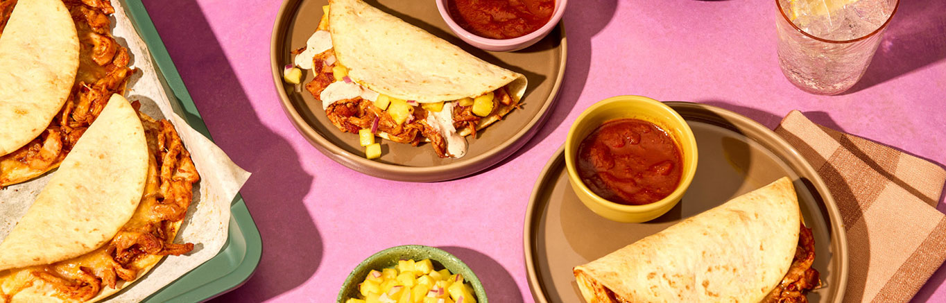 An image of prepared Sheet Pan Chipotle Chicken Tacos made with chicken thighs, Pace® Chipotle Picante Sauce, sour cream, cilantro, flour tortillas and Mexican blend cheese.