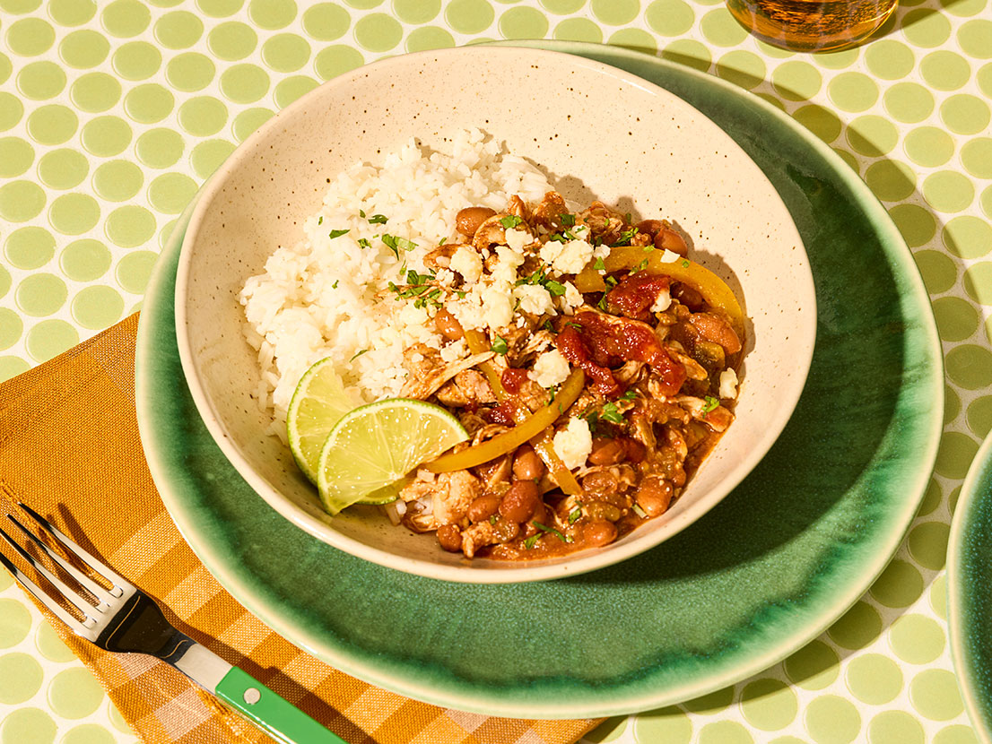 An image of prepared Slow Cooker Chipotle Chicken Chili made with chicken thighs, pinto beans, Pace® Chipotle Picante Sauce, green chiles, bell pepper, garlic and white rice.