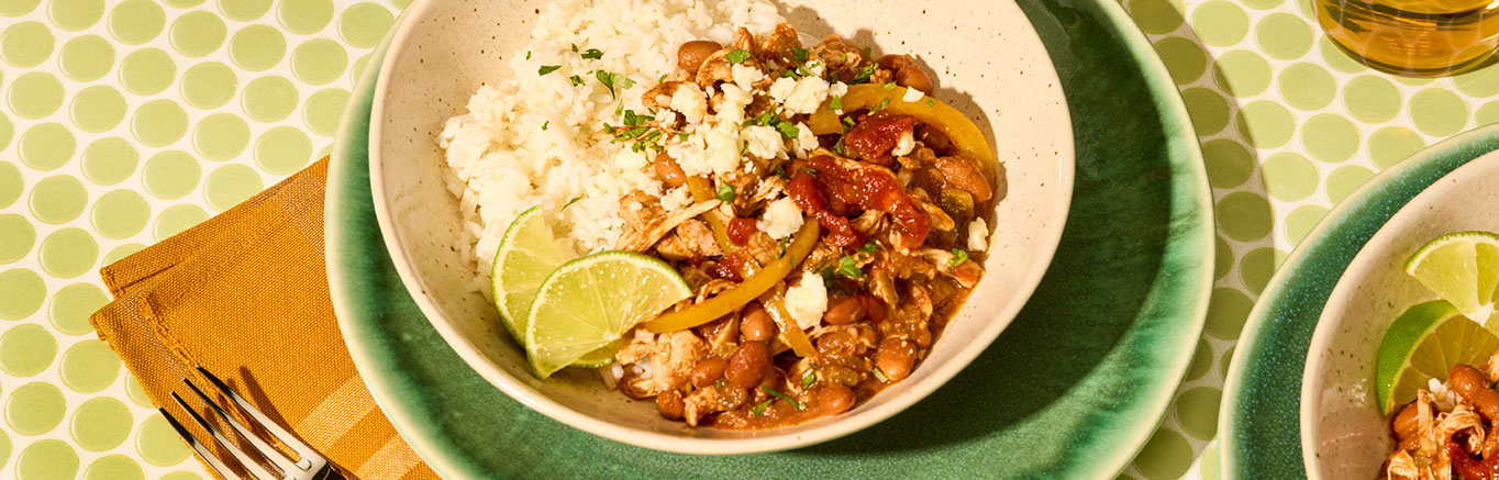 An image of prepared Slow Cooker Chipotle Chicken Chili made with chicken thighs, pinto beans, Pace® Chipotle Picante Sauce, green chiles, bell pepper, garlic and white rice.