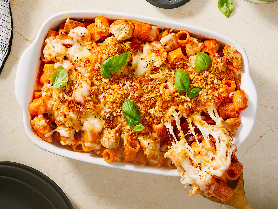 Image of prepared Chicken Parmesan Casserole made with chicken, Prego® Creamy Tomato with Ricotta Sauce, Swanson® Unsalted Chicken Broth, mezzi rigatoni, mozzarella cheese, grated Parmesan and basil.