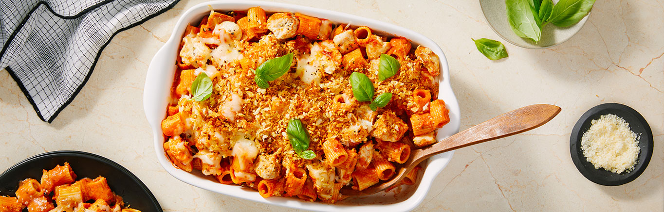Image of prepared Chicken Parmesan Casserole made with chicken, Prego® Creamy Tomato with Ricotta Sauce, Swanson® Unsalted Chicken Broth, mezzi rigatoni, mozzarella cheese, grated Parmesan and basil.