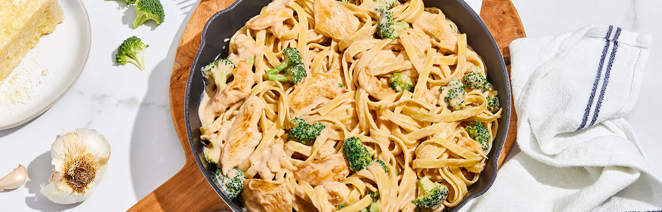 An image of prepared Chicken Broccoli Alfredo with Fettucine in a skillet made with fettuccine, chicken, broccoli and Prego® Roasted Garlic Parmesan Alfredo or Homestyle Alfredo Pasta Sauce.