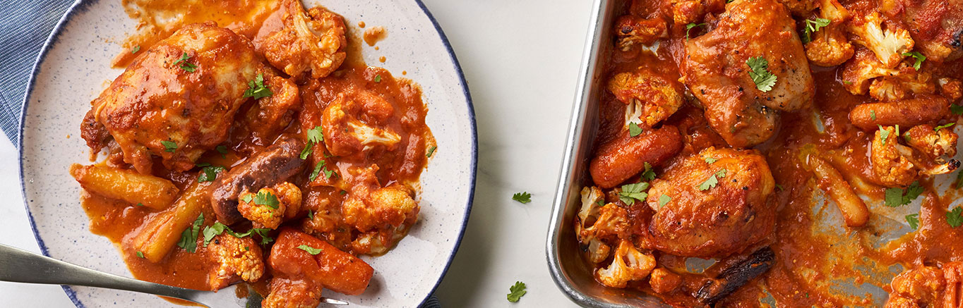 An image of prepared Spicy Sheet Pan Indian Butter Chicken made with Prego® Spicy Vodka Sauce, curry powder, chicken thighs, cauliflower and cilantro.