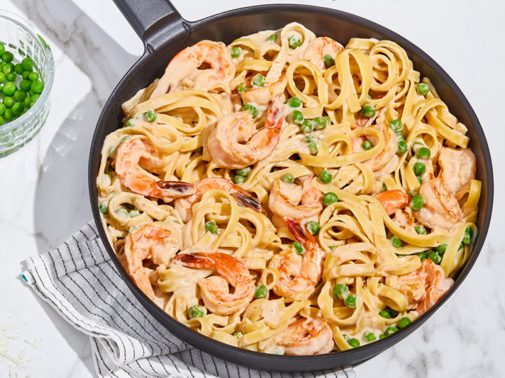 An image of prepared Shrimp Alfredo made with fettuccine pasta, shrimp, Prego® Homestyle Alfredo Sauce, peas and basil.