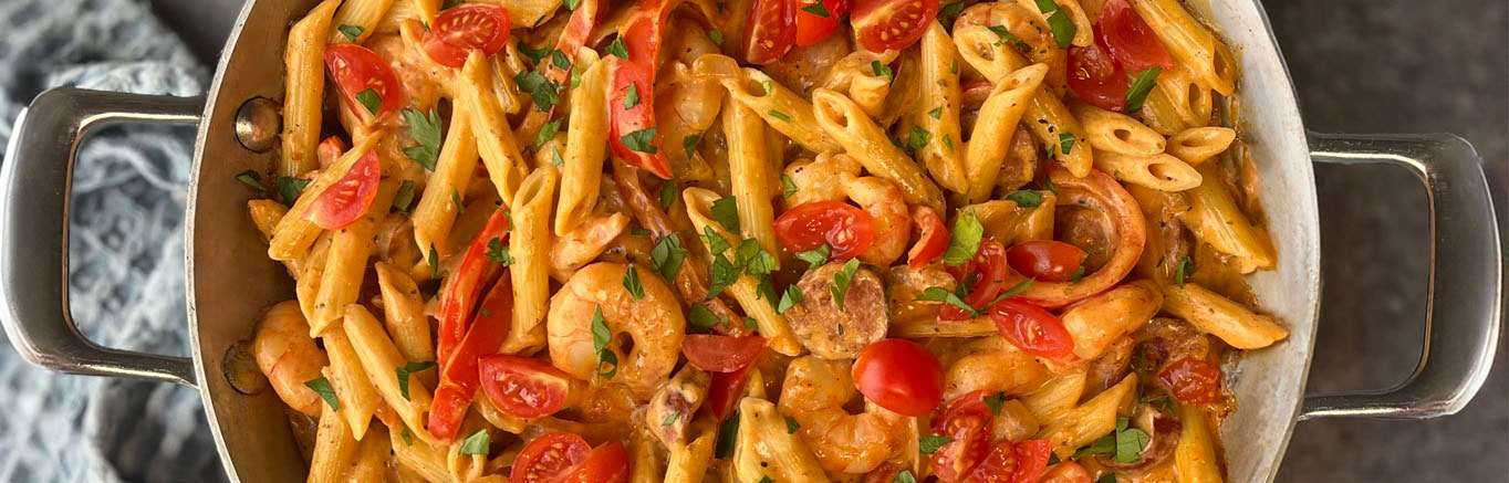 An image of Skillet Cajun Shrimp Alfredo made with Prego® Homestyle Alfredo Sauce, penne pasta, andouille sausage, bell pepper, shrimp, Cajun seasoning and tomatoes.