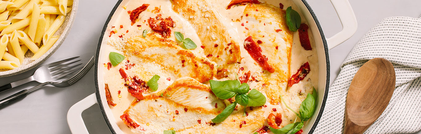 An image of prepared Marry Me Chicken Alfredo made with Prego® Homestyle Alfredo Sauce, chicken, sun-dried tomatoes, onion, Parmesan and basil.