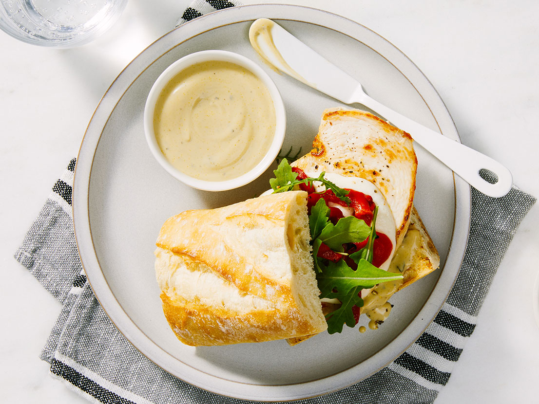 An image of prepared Creamy Pesto Chicken Sandwiches made with chicken, Prego® Creamy Basil Pesto Sauce, mozzarella, arugula and French baguette.