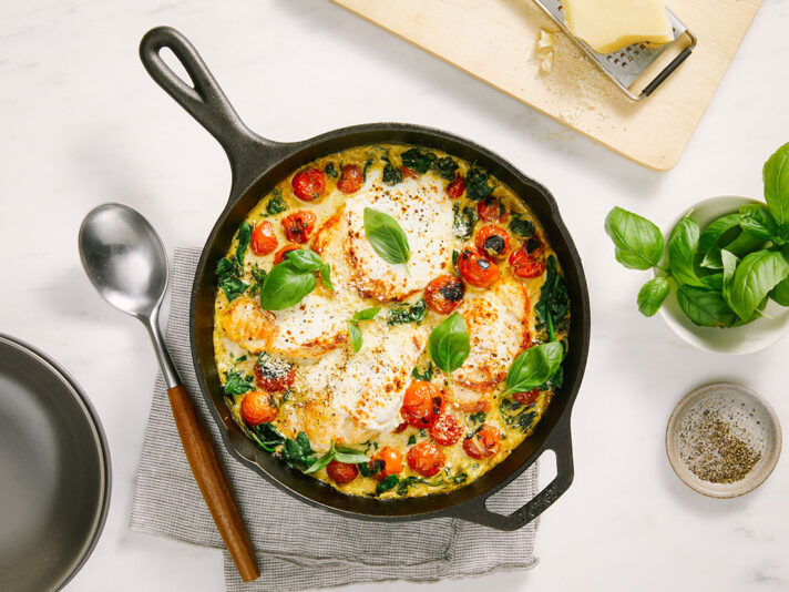 An image of prepared Skillet Creamy Pesto Chicken Caprese made with chicken, tomatoes, Prego® Creamy Parmesan Pesto Sauce, spinach, mozzarella and Parmesan cheese.
