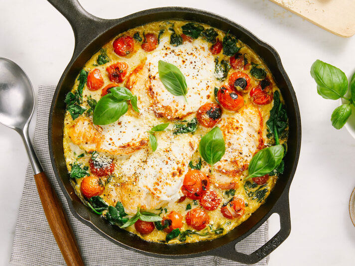 An image of prepared Skillet Creamy Pesto Chicken Caprese made with chicken, tomatoes, Prego® Creamy Parmesan Pesto Sauce, spinach, mozzarella and Parmesan cheese.